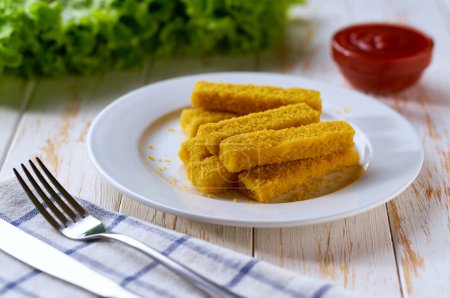Foto de Crujientes dedos de pescado frito dorado palos con salsa de limón y tomate en la mesa de madera. - Imagen libre de derechos