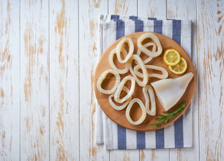Photo for Sliced rings raw squid with lemon on a white table. Top view. - Royalty Free Image