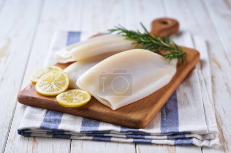 Photo for Fresh raw squid or cuttlefish fillet on a wooden table, selective focus. - Royalty Free Image