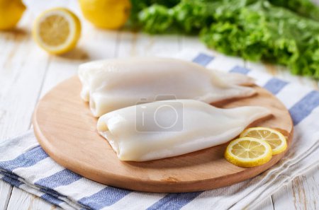 Photo for Fresh raw squid fillet with lemons on a wooden table selective focus. - Royalty Free Image
