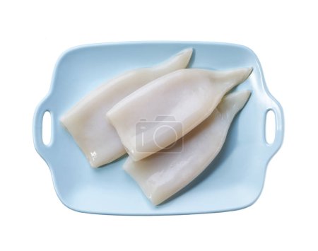 Téléchargez les photos : Filet de seiche ou calmar cru frais dans une assiette bleue isolée sur fond blanc. - en image libre de droit