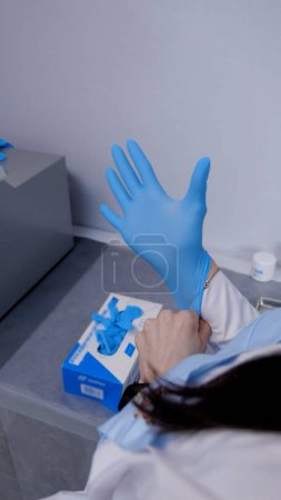 Photo for Doctor or nurse worker surgeon preparing for the surgical operation and wearing hand gloves at health clinic or hospital office. Social distancing, quarantine for coronavirus - Royalty Free Image