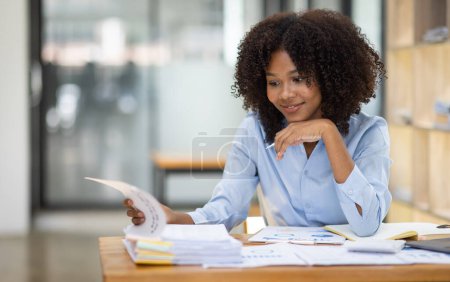 Téléchargez les photos : Succès afro-américain comptable femme d'affaires documents de travail taxe sur l'ordinateur portable dans le bureau. finance investissement économie et commercialisation recherche concept. - en image libre de droit