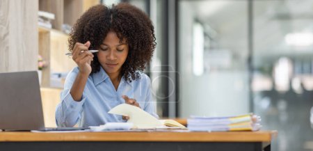 Téléchargez les photos : Succès afro-américain comptable femme d'affaires documents de travail taxe sur l'ordinateur portable dans le bureau. finance investissement économie et commercialisation recherche concept. - en image libre de droit