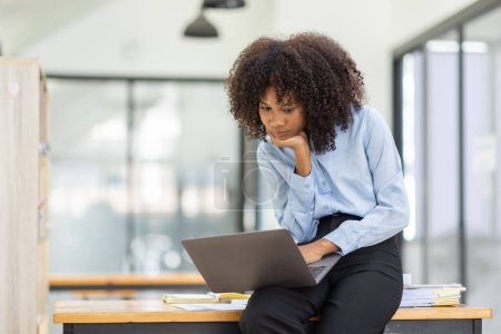 Téléchargez les photos : Belle femme d'affaires africaine asiatique faire une vidéoconférence par ordinateur portable et assis au bureau, - en image libre de droit
