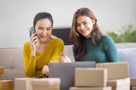 Téléchargez les photos : Deux femmes asiatiques au démarrage d'une petite entreprise PME entrepreneur de freelance travaillant sur ordinateur portable avec boîte de colis sur ordinateur portable de table à la maison, emballage de marketing en ligne et concept d'idée de PME de livraison - en image libre de droit