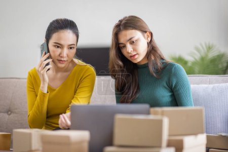 Téléchargez les photos : Deux femmes asiatiques au démarrage d'une petite entreprise PME entrepreneur de freelance travaillant sur ordinateur portable avec boîte de colis sur ordinateur portable de table à la maison, emballage de marketing en ligne et concept d'idée de PME de livraison - en image libre de droit