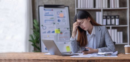 Téléchargez les photos : Les jeunes femmes asiatiques d'affaires sont stressées tout en travaillant sur un portable Femme d'affaires asiatique fatiguée avec des maux de tête au bureau, se sentant triste ou malade au bureau de copie de travail. - en image libre de droit