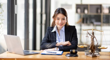 Foto de Business Asian woman in suit and Lawyer working on a documents at workplace office. Judge gavel with Justice lawyers,  Legal law, advice  and justice concept - Imagen libre de derechos