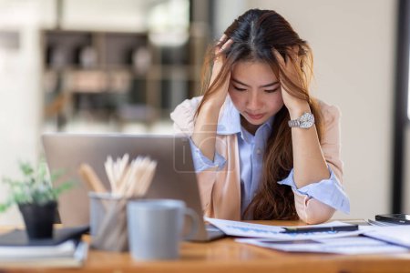 Téléchargez les photos : Les jeunes femmes asiatiques d'affaires sont stressées tout en travaillant sur un ordinateur portable, Femme d'affaires asiatique fatiguée avec des maux de tête au bureau, se sentant malade à l'espace de copie de travail dans un bureau à domicile. - en image libre de droit