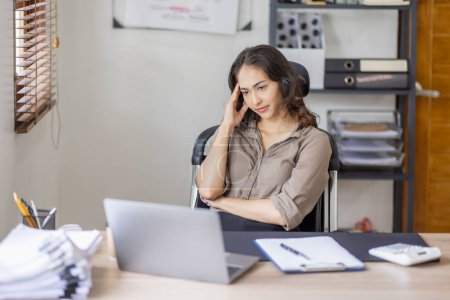 Téléchargez les photos : Les femmes indiennes asiatiques sont stressées tout en travaillant sur un ordinateur portable, Fatiguée femme d'affaires asiatique avec des maux de tête au bureau, se sentant malade au travail copie espace dans le lieu de travail un bureau à domicile. - en image libre de droit