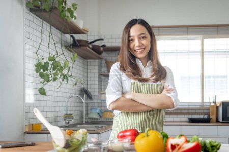 Téléchargez les photos : Portrait de femme japonaise asiatique attirante dans la cuisine à la maison, jeune fille naviguant sur le site de tuteur cours de cuisine et de faire pour la cuisine, couper les légumes, cuisine, concept de cuisine. - en image libre de droit