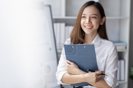 Téléchargez les photos : Young business Asian woman holding document file and stand in home office - en image libre de droit