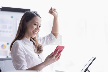 Téléchargez les photos : Happy Asian woman holding a smartphone and winning the prize, asian female happy excited in workplace office - en image libre de droit