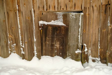 Téléchargez les photos : Partie d'une ancienne grange avec des portes en bois marron et beaucoup de neige - en image libre de droit