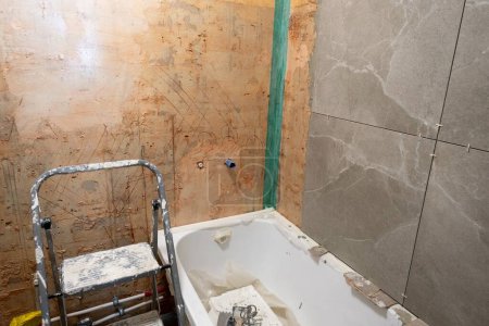 Photo for Bathroom renovation. The tiles have been removed, the walls are ready for repair. new bath. - Royalty Free Image