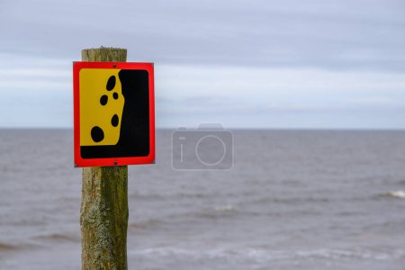 Téléchargez les photos : Un signe d'avertissement d'un possible glissement de terrain près du bord de mer. Reflète l'idée du concept de prudence et de signes d'avertissement - en image libre de droit