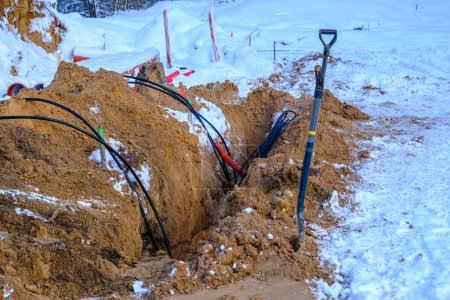 Téléchargez les photos : Urgent repairs during the winter. Electric cable replacement. A pile of sand, a cable and a shovel for digging the ground. - en image libre de droit
