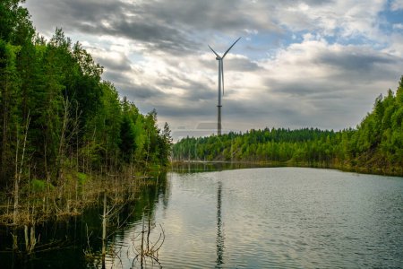 Photo for This is a former shale quarry with azure water and picturesque hills. Unlike the Narva shale settling ponds. A dark autumn day. Estonia, Aidu quarry. A tall wind turbine in the distance. - Royalty Free Image