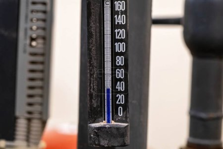 Nahaufnahme eines Thermometers, das in einer industriellen Umgebung etwa 100 ° C anzeigt