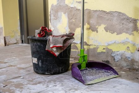 Photo for A dirty mop and bucket amidst a room undergoing renovation with peeling paint and debris. - Royalty Free Image