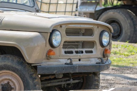 A close-up view of a vintage off-road vehicle with a rugged design, showcasing its headlight and grille details.