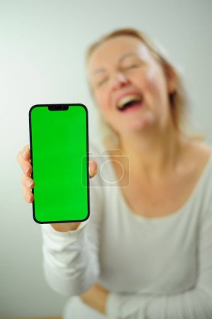 Photo for Winning to find what to look for joy happiness different emotions Chroma Key Phone green screen space for advertising Photo of woman in white shirt on a white background Beautiful adult happy woman - Royalty Free Image