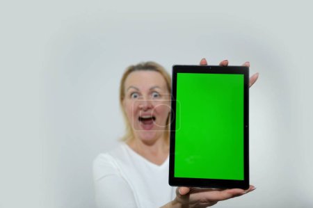 Téléchargez les photos : Happy caucasian woman student freelancer holding showing digital tablet with green mockup screen for ad copyspace isolated in white background. High quality photo - en image libre de droit