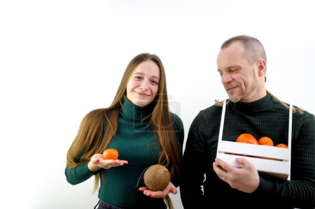 Photo for Comic photo different size of breasts one breast is larger than the other is smaller girl holding fruit tangerine and cocoas smiling man next to a basket in form of box looks at teenage joke instead - Royalty Free Image