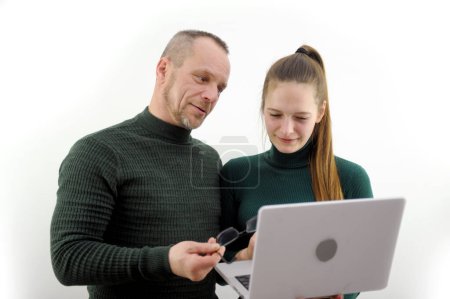 Photo for Middle-aged man shows girl with glasses picture in laptop student young beautiful hairstyle from pawned hair listens to professor from laptop in hands man neatly in short hairstyle with girl points - Royalty Free Image