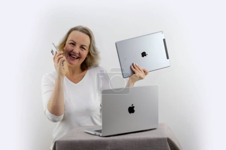 Foto de Mujer de la celebración de Apple gadgets que tiene iPad MacBook y el teléfono que iPhone 13 promax Ella mira a la tableta iPad y sonrisas comprar regalos compra venta publicidad última tecnología Ucrania 2023 - Imagen libre de derechos