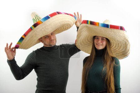 Photo for Adult man and young girl hold on their heads sombrero hat spanish headdresses joy buy at time in dark green golfs on walk headdress sale clothes joyfully journey mexican holiday buenos muchachos - Royalty Free Image