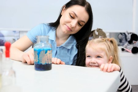 Téléchargez les photos : Little scientist. Curious daughter play with mom engaged at education activity make funny experiment. Interested small girl watch elder sister doing chemical test use chemistry set kids - en image libre de droit