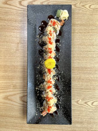 Foto de Sushi con cangrejo y camarones en plato negro decorado con una flor amarilla - Imagen libre de derechos