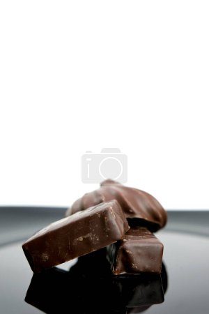 Téléchargez les photos : Chocolats sur une plaque noire espace de fond blanc pour le texte sucreries verticalement délicieux au lieu de la publicité Cubes de barre de chocolat au lait isolé sur fond blanc. Haute qualité - en image libre de droit
