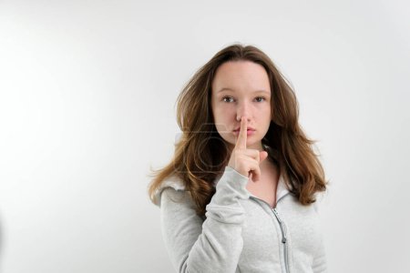 Photo for Young woman says ssshhh to maintain silence on a white background. High quality photo - Royalty Free Image