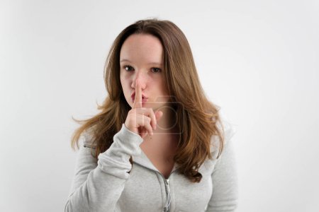 Photo for Young woman says ssshhh to maintain silence on a white background. High quality photo - Royalty Free Image