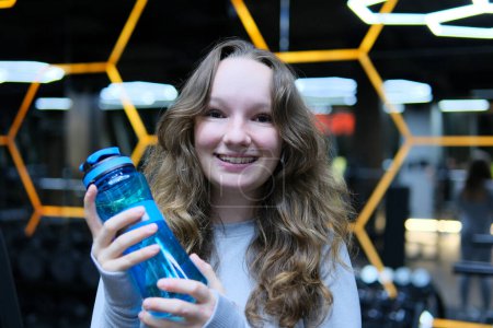 Téléchargez les photos : Adolescente tenant une bouteille d'eau. Studio abattu, isolé. Photo de haute qualité - en image libre de droit