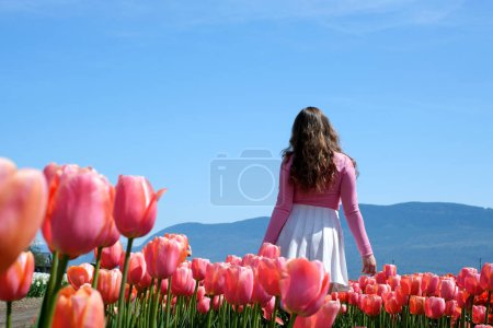 Téléchargez les photos : Une fille jouant dans un jardin de fleurs avec arc-en-ciel - en image libre de droit