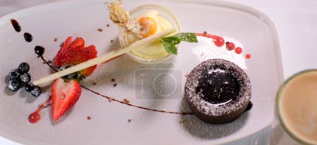  Schokoladenfondant mit Erdbeeren und Löffel auf Teller, isoliert auf weißem Hintergrund, Draufsicht