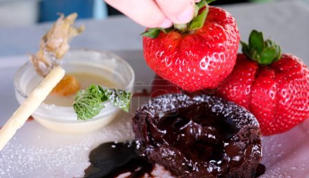  Schokoladenfondant mit Erdbeeren und Löffel auf Teller, isoliert auf weißem Hintergrund, Draufsicht
