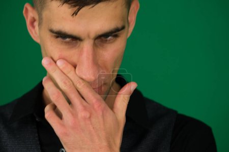 Afraid young guy in yellow T-shirt looking through fingers, white isolated background. Scared face of young man in yellow T-shirt on white background. Portrait of frighten