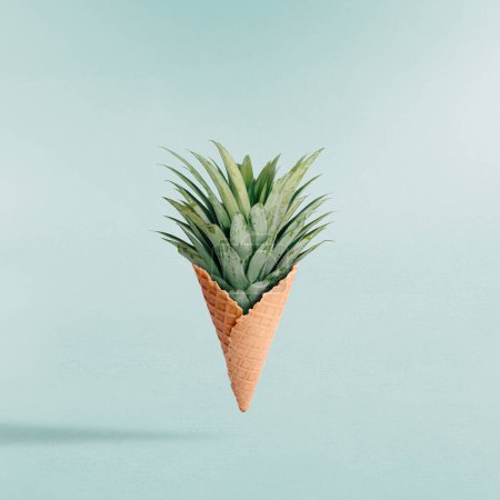 Téléchargez les photos : Composition estivale avec cône de crème glacée et feuilles d'ananas vert sur fond clair. Concept créatif abstrait d'aliments sucrés. Fruits et bonbons pop art esthétique. - en image libre de droit