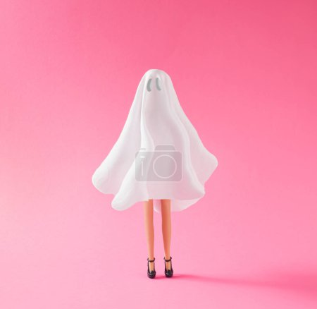 Téléchargez les photos : Fille en costume fantôme sur fond rose pastel. Halloween partie concept minimal. - en image libre de droit