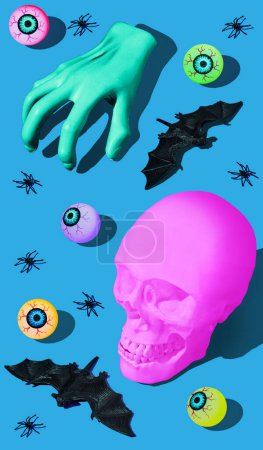 Foto de Halloween concepto de horror con cráneo rosa, mano zombie, arañas, murciélagos y globos oculares. Fondo azul - Imagen libre de derechos