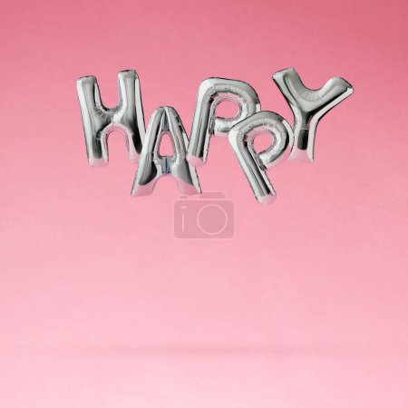 Foto de Los globos de helio en forma de carta flotan sobre un fondo rosado pastel y deletrean la palabra FELIZ. Concepto de celebración mínima. - Imagen libre de derechos