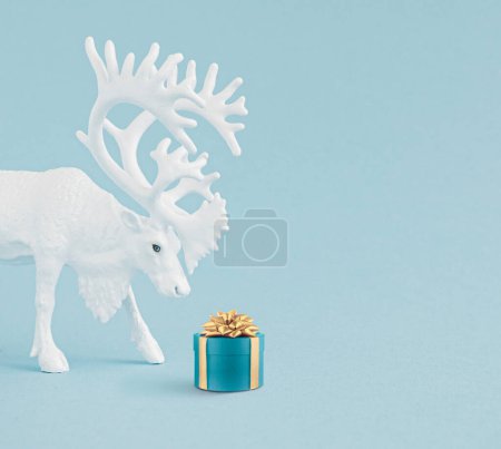Foto de Concepto creativo de Navidad hecho con renos blancos con caja de regalo azul de Navidad y lazo amarillo sobre fondo azul pastel Concepto mínimo de vacaciones de Navidad y Año Nuevo - Imagen libre de derechos