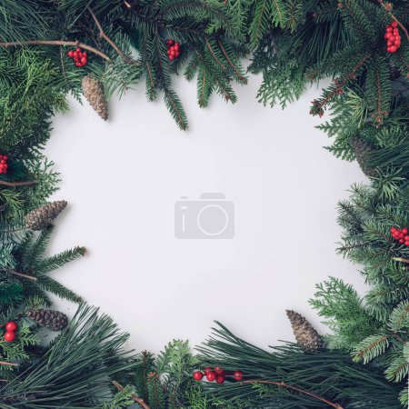 Foto de Patrón navideño de moda hecho con bayas rojas y ramas de pino sobre fondo claro con espacio para escribir - Imagen libre de derechos