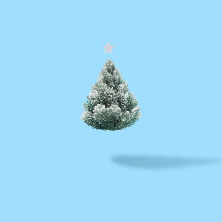Téléchargez les photos : Mise en page créative avec arbre de Noël enneigé sur fond bleu vif. Minimal hiver nature vacances scène - en image libre de droit