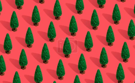Téléchargez les photos : Composition minimale fond de motif des arbres de Noël verts sur rouge pastel. Concept Nouvel An. - en image libre de droit